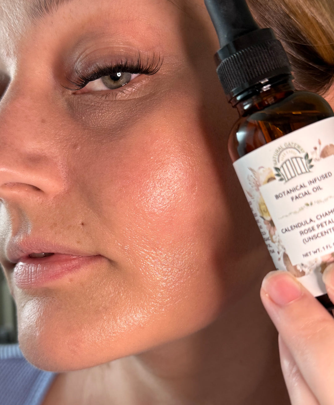 Close-up of a person applying a facial oil dropper to their face.